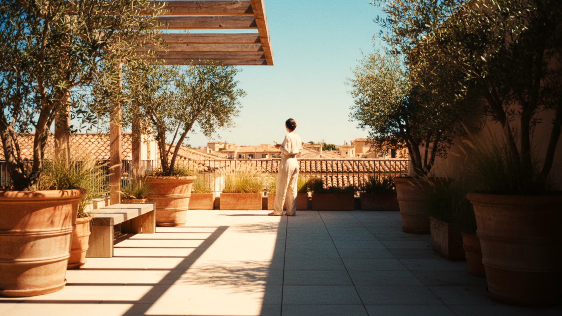 illustration: a rooftop terrace in strong afternoon sun, a pergola throwing hard-edged stripes of shadow across pale concrete